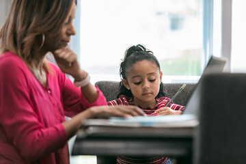 Home: Little Girl Doing Math Homework While Mother Works Remotel