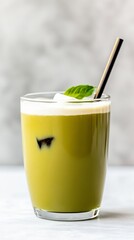A glass of iced matcha latte with coconut milk, garnished with mint.