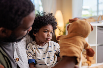 Male caretaker showing glove puppet to cute boy
