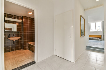 A sleek and modern interior hallway showcasing a blend of minimalist design elements, contrasting color schemes, and functional space. A view into a well-lit area enhances the aesthetic.