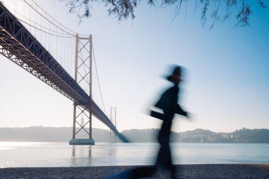 Blurred Silhouette of a Runner Under a Suspension Bridge