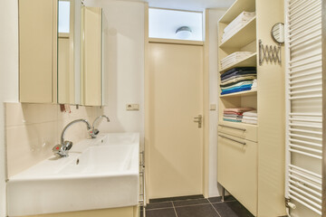 Stylish and minimalist bathroom featuring sleek cabinetry, organized towels, and contemporary fixtures, creating a vibrant yet serene ambiance.