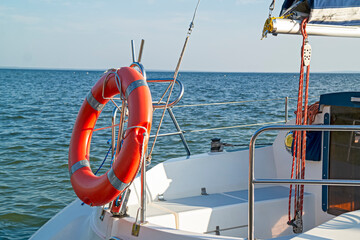 Yacht Travel Cruises With Mast and Red life-Buoy Against Blue Skies.