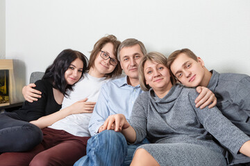 Fototapeta premium Smiling Happy Caucasian Family Get Together Embracing and Sitting on Sofa Indoors With Positive Expression