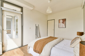 A bright, modern bedroom featuring a neatly made bed, minimal decor, and large windows that invite natural light, creating a serene and inviting atmosphere.