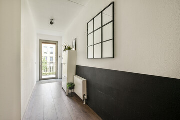 A sleek and stylish hallway featuring a mix of light and dark walls, a cabinet, and a large mirror. Ideal for showcasing modern minimalistic decor.