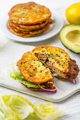 Homemade avocado bun, glutenfree flat bread with patty, lettuce, onion and cream cheese