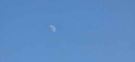 A clear blue sky featuring a crescent moon. Ideal for astronomy, nature themes, or artistic uses in educational content, digital designs, and decor.