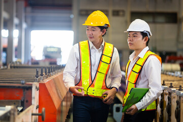 Unity and teamwork. Asian team engineer worker working control sheet metal roof tile roll forming machine at metal sheet profiling factory. Industrial production