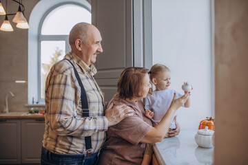 Fototapeta premium Grandmother, grandfather and granddaughter playing together at home on the window portrait