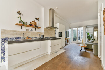 A stylish modern kitchen featuring sleek cabinetry, wooden flooring, and large windows that bring in natural light, creating an open and inviting atmosphere.