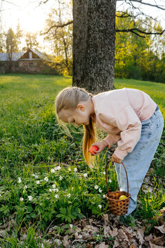 Child collecting easter eggs in spring meadow