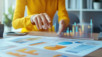 Fototapeta premium Digital Marketing Spend Concept. A person in a yellow sweater interacts with colorful charts and graphs on a desk, showcasing data analysis and business insights.