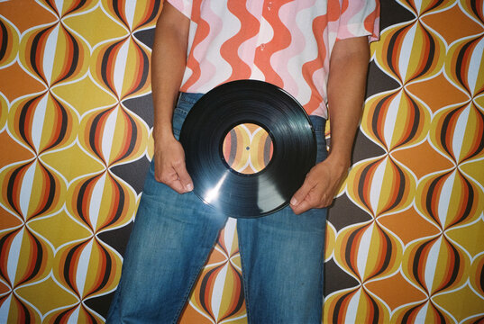 man holds a disc in front of a geometric wall, 35mm