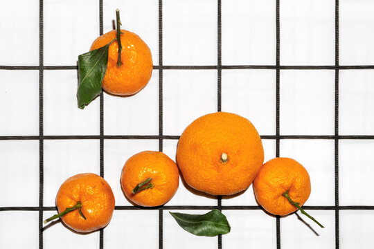 Fresh orange mandarins with green leaves on a checkered background. 