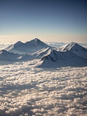 Naklejka premium Snowy Mountain Peaks Above Clouds