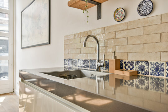 A stylish modern kitchen featuring a sleek countertop, decorative tiles, and minimalistic design elements. The space blends functionality and aesthetics effortlessly.