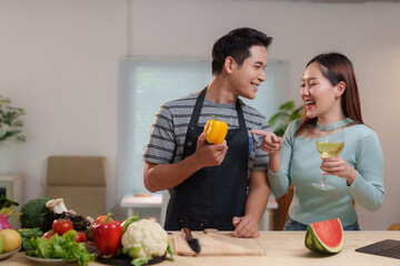 Asian couple having fun cooking together in modern kitchen