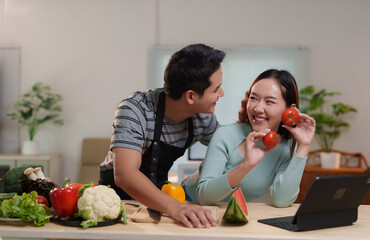 Asian couple having fun cooking together in modern kitchen