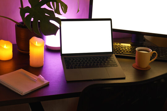 Cozy home office setup with modern laptop and ambient lighting. 