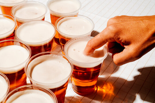 man puts his finger into a cup with beer