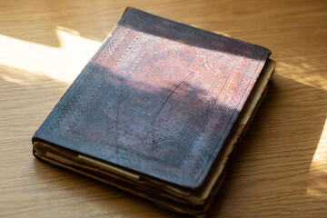 There is a book that has a brown cover sitting atop a wooden table