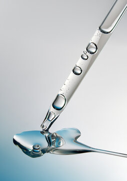 Close up of a pipette with liquid on reflective blue background.