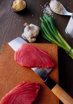 Freshly sliced tuna with garlic and green onions atop a wooden cutting