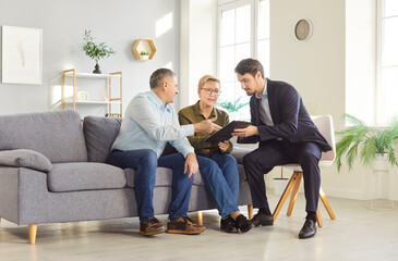 Senior couple engaged in negotiations with a consultant or agent regarding contracts for insurance...