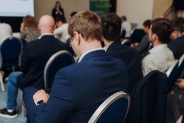 Audience at the modern conference hall listens to panel discussion, people on a congress together...