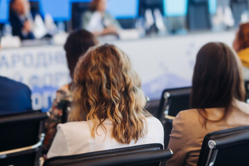 Audience at the modern conference hall listens to panel discussion, people on a congress together...