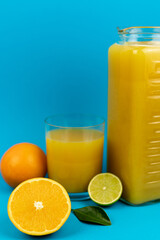 Glass of orange juice in glass close-up. Cut oranges on the table.