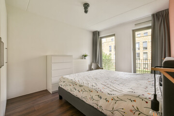 A contemporary bedroom featuring a minimalistic design, ample natural light from large windows, and stylish furnishings for comfort and aesthetics.