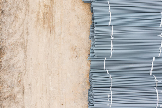 Stack of Grey Pipes Bundled with White Straps on Rough Ground