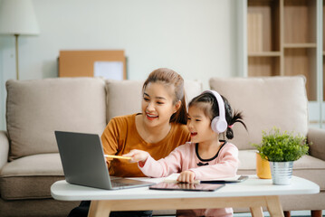 A caring mother and young daughter share a bonding moment doing homework at home.