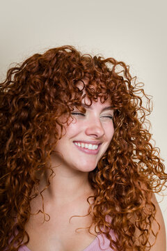 Portrait of woman with long curly red hair winking