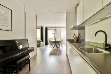 A stylish modern kitchen featuring sleek cabinetry and an open layout that connects to a comfortable living area with a view of the outdoors.