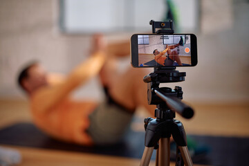 Close up of male coach filming his exercise vlog with mobile phone.
