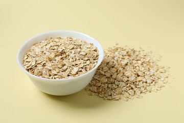 Composition with oatmeal flakes on beige background. Cooking breakfast