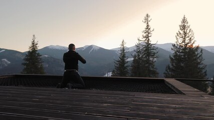 Man meditating in the mountains, peaceful winter scenery with trees and snowy peaks