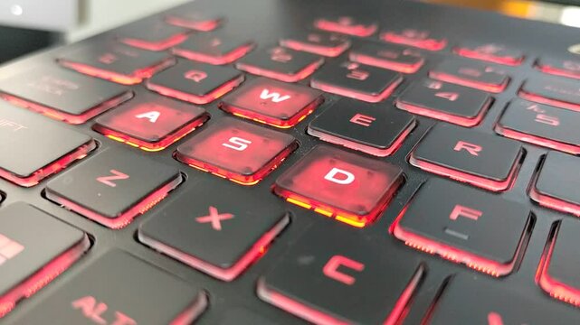 Laptop keyboard close-up. The most common gaming keys, W, A, S, and D, used for directional input, known as the WASD keys. Has the red backlight.