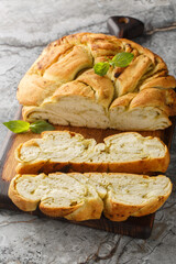 Delicious Pesto Bread is a soft and fluffy homemade bread that has swirls of fragrant basil pesto throughout closeup on the wooden board on the table. Vertical