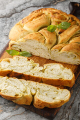 Homemade bread is braided with basil pesto closeup on the wooden board on the table. Vertical