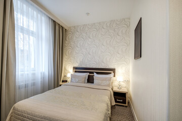 double bed with pillows in interior with night lamp in hotel room..