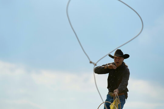 Cowboy skillfully swinging a lasso under a clear blue sky during a rodeo event. Brandenburg, Germany