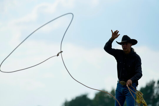 Cowboy skillfully twirling a lasso in an outdoor setting under a clear blue sky. Brandenburg, Germany