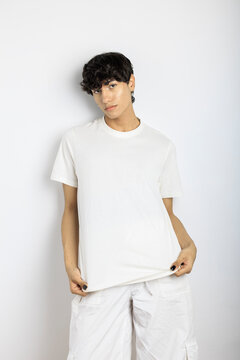 Androgynous person showing white t-shirt posing over white wall
