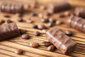 Coffee beans and chocolate bars on wooden background, closeup