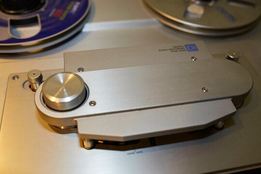 Close-up of a vintage reel-to-reel tape recorder with metal components and controls.