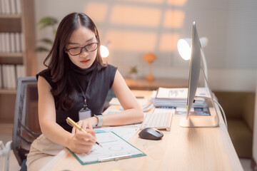 Asian businesswoman wearing glasses and working with financial chart, analyzing sales data and...